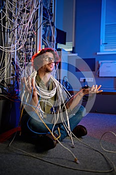 Sad, puzzled technician holding many cables in hand trying to solve problem
