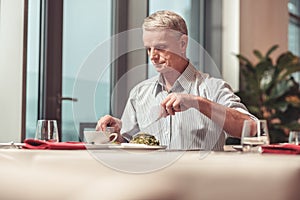 Sad retired man eating a salad in a restaurant