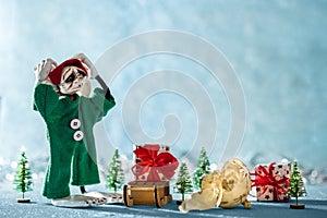 Sad Santas Helper Elf With Head in Hands Standing Next to a Broken Christmas Bauble. North Pole Christmas Scene. Santas Workshop.