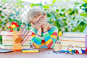 Sad school kid boy with glasses and student stuff