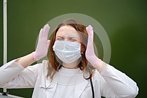 Sad school nurse in a medical mask on a blackboard