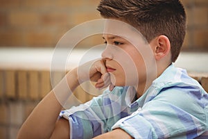 Sad schoolboy sitting alone on steps in campus