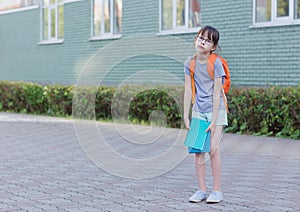 Schoolgirl backs to school. Portrait of tired child with backpack and notebook photo