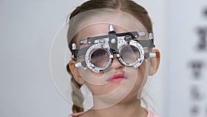 Sad schoolgirl in optical trial frame, eyesight testing, eyeglasses prescription