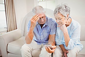 Sad senior couple looking at mobile phone