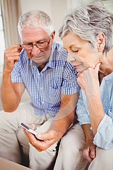 Sad senior couple looking at mobile phone