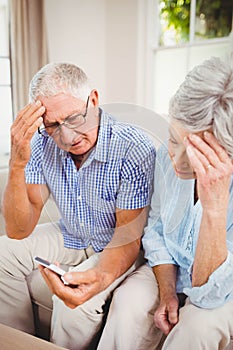 Sad senior couple looking at mobile phone