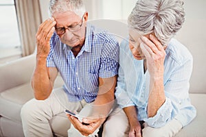 Sad senior couple looking at mobile phone