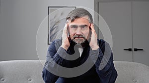 Sad senior man with headache sitting alone in a empty room