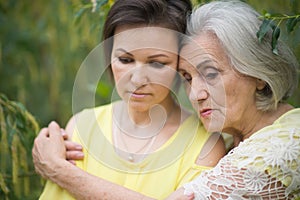 Sad senior woman with adult daughter in park