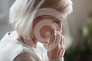 Sad senior woman mourning crying wiping tears grieving lost love