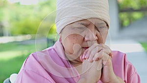 Sad, senior woman and person with Cancer sitting in a wheelchair, stress and crying into her hands at the hospital park,