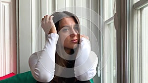 Sad sepressed young woman crying sitting on a window at home