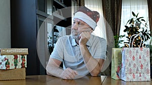 Sad serios beared senior man in red christmas hat looking to the side