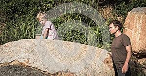 Sad serious boy bored climbed hiding on stone. Loving father wants to help. Family relations closeness daddy son