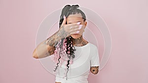 Sad and serious hispanic amputee woman shielding her sightless eyes, standing in denial against isolated pink background, her hand