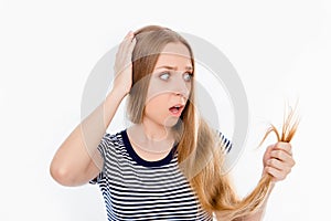 Sad shocked girl looking at her damaged hair