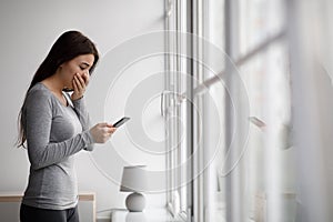 Sad shocked upset scared european millennial woman reading message on phone with bad news at home