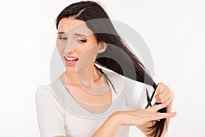 Sad shoked young woman cutting her long hair