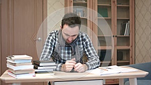 Sad and sick student getting down with flu sitting at the desk with books