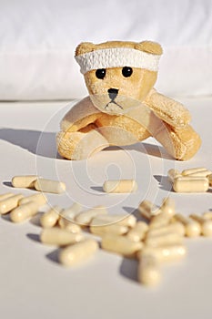 Sad, sick Teddy Bear among pills.