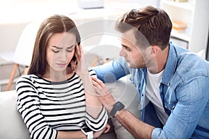 Sad sick woman sitting on the couch with her boyfriend