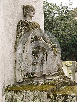 Sad sitted sculpture of a woman looking at the horizon in a tomb in the Pere Lachaise cemetery. All Saints Day, November 1, Day of