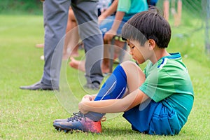 Soccer kid sitting on field side substitution bench doesn`t get to play in a competition match photo