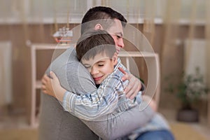 Sad son hugging his dad indoor