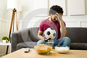 Sad sports fan losing the game with his favorite soccer team