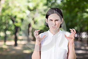 A sad and stressed female on a natural background. An angry lady holding her hands up. Misunderstanding and frustration concept.