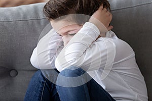 Sad stressed stubborn little kid boy sit alone closing ears