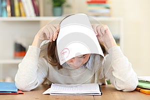 Sad student with a failed exam at home