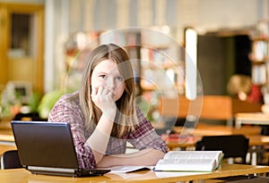 Sad student with laptop working in library