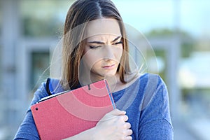 Sad student looking down walking in a college