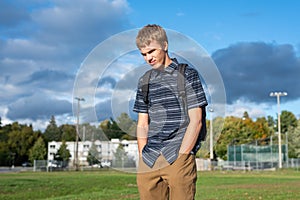 Sad student standing in a park.