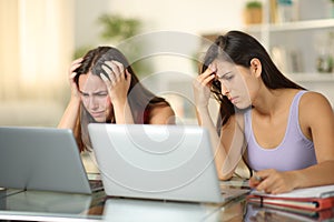 Sad students checking grades on laptops at home photo
