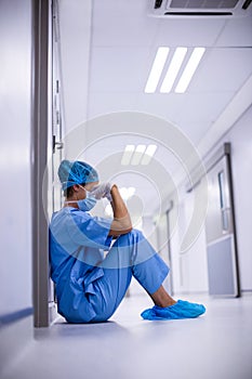 Sad surgeon sitting on floor in corridor