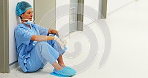 Sad surgeon sitting on floor in corridor