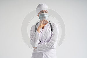 Sad surprised doctor wearing medical face mask holding medical thermometer over white background