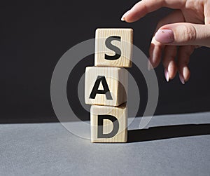 Sad symbol. Wooden cubes with words Sad. Businessman hand. Beautiful grey background. Business and Sad concept. Copy space