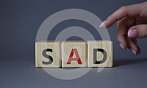 Sad symbol. Wooden cubes with words Sad. Businessman hand. Beautiful grey background. Business and Sad concept. Copy space