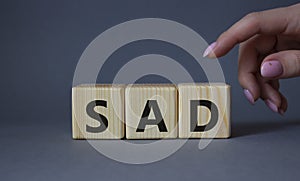 Sad symbol. Wooden cubes with words Sad. Businessman hand. Beautiful grey background. Business and Sad concept. Copy space