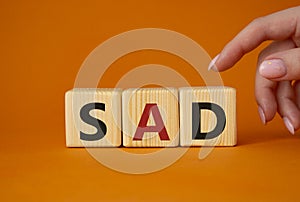 Sad symbol. Wooden cubes with words Sad. Businessman hand. Beautiful orange background. Business and Sad concept. Copy space