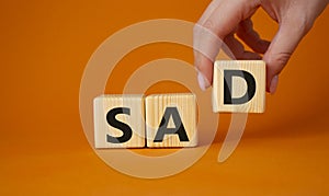 Sad symbol. Wooden cubes with words Sad. Businessman hand. Beautiful orange background. Business and Sad concept. Copy space