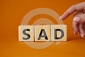 Sad symbol. Wooden cubes with words Sad. Businessman hand. Beautiful orange background. Business and Sad concept. Copy space