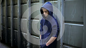 Sad teen boy hiding from everyone in backstreet, adolescent protest against word