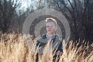 Sad teen boy sweatshirt on fall nature in aunumn day. Teenager is immersed in his thoughts and reflections. Teenagerhood