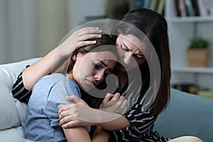 Sad teen crying being comforted by her sister at home photo