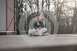 Sad teen girl on a bench in the park. Single girl outdoor. Lonely sad girl